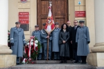 Wspólne zdjęcie kilku członków Związku Piłsudczyków, profesor Sabiny Bober i duchownego. Wszyscy stoją przed gmachem Urzędu Miasta, Piłsudczycy ubrani są w mundury  a jeden z nich trzyma sztandar