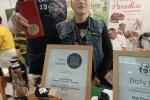 mężczyzna i kobieta ubrani na czarno na stanowisku promocyjnym trzymający medal