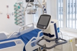 Wnętrze sali szpitalnej z widokiem na jedno łóżko i specjalistyczną aparaturę ustawionąobok