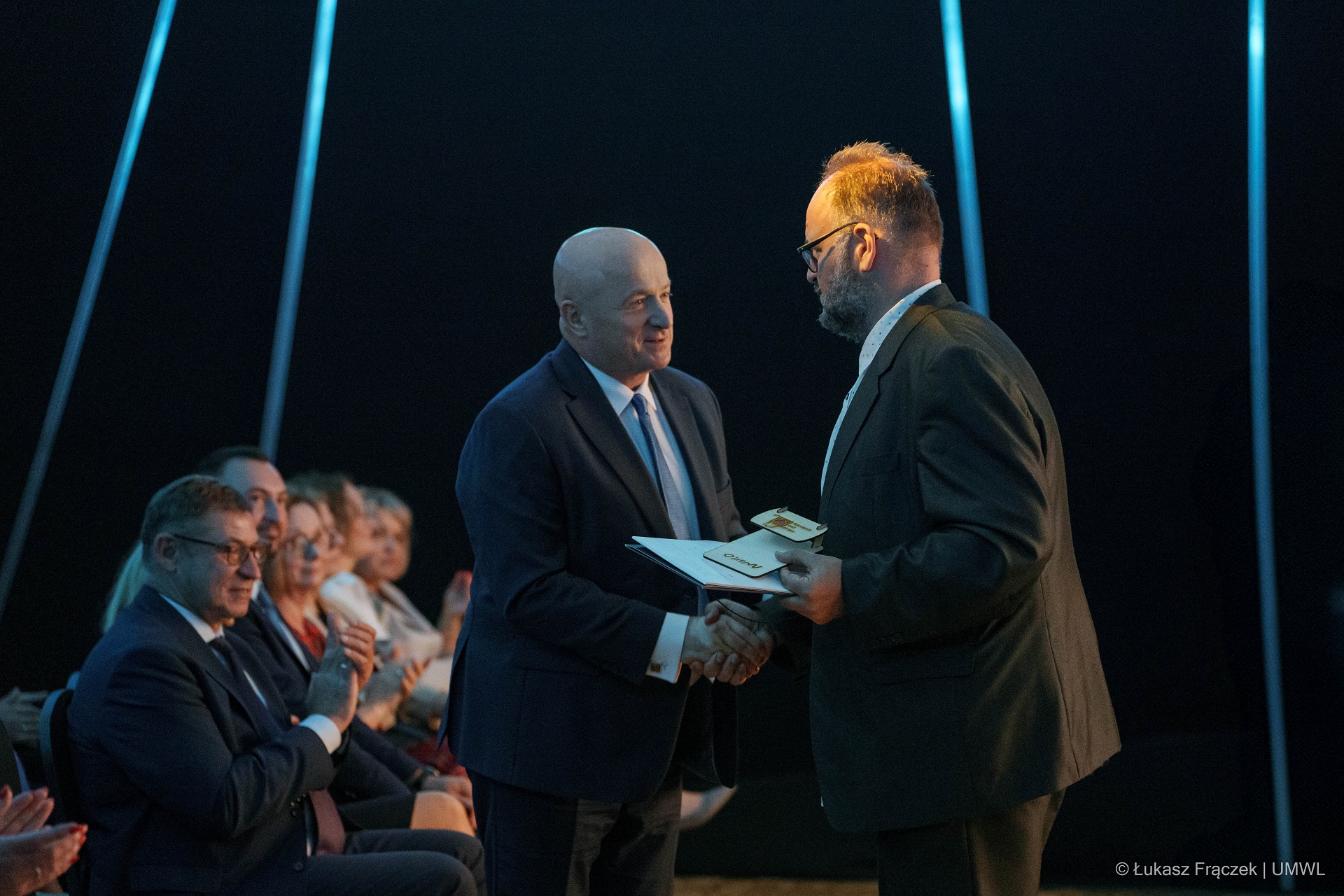 Na scenie pozuje wspólnie kilkunastu laureatów certyfikatu, za nimi na dużym ekranie wyświetla się napis Gala Zakup  Prospołeczny 2024