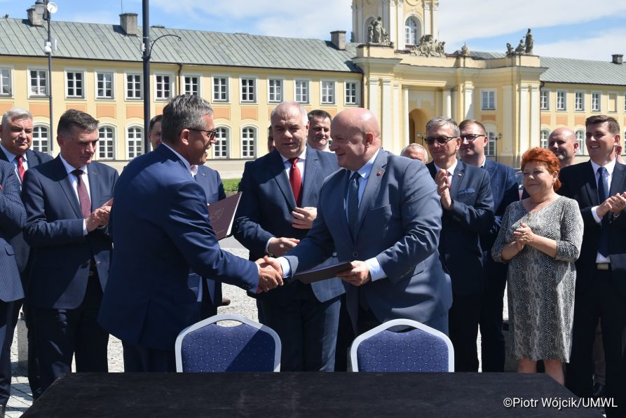 Podpisanie umowy na reitalizację Zespołu Pałacowego Potockich w Radzyniu Podlaskim. Umowę podpisali (od lewej) Burmistrz Radzynia Podlaskiego Jerzy Rębek i Marszałek Województwa Lubelskiego Jarosław Stawiarski. Za nimi stoi grupa ludzi, wśród nich jest (od lewej) Wojewoda Lubelski Lech Sprawka oraz Wicepremier Jacek Sasin. W tle Pałac Potockich.