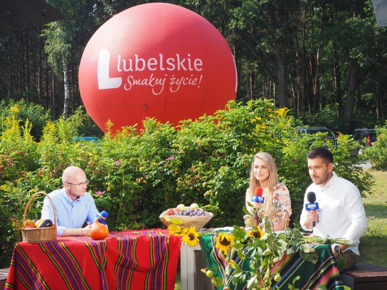 Zdjęcie przedstawiające dwójkę dziennikarzy siedzących przy stole wraz z Członkiem Zarządu Sebastianem Trojakiem.