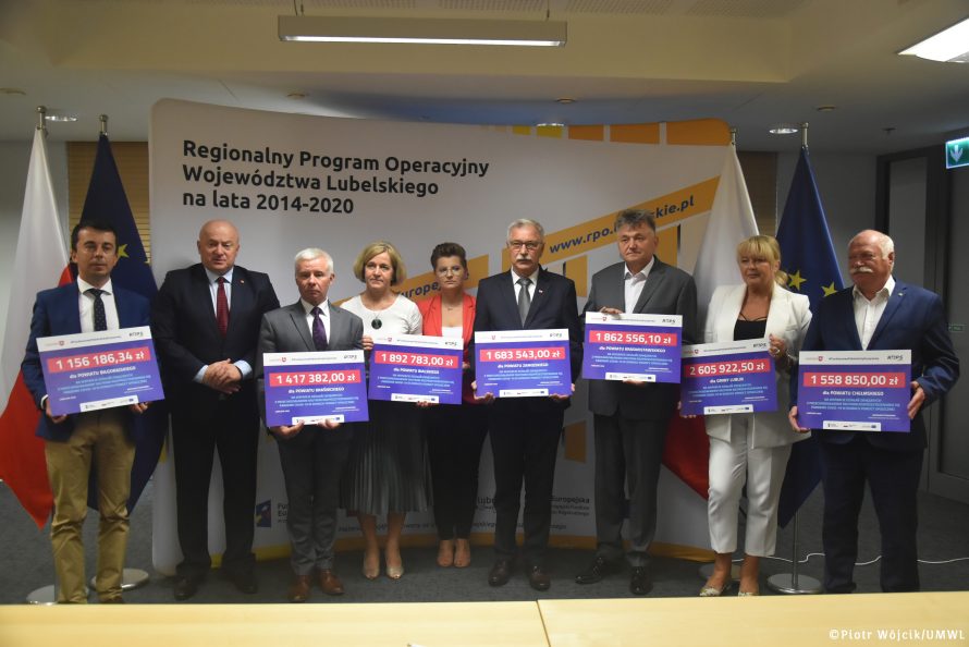 Przekazanie czeków na realizację działań związanych z przeciwdziałaniem skutkom rozprzestrzeniania się pandemii Covid-19 w domach pomocy społecznej. Od lewej: Andrzej Szarlip starosta biłgorajski, Marszałek Jarosław Stawiarski, Andrzej Rolla Starosta Kraśnicki, Małgorzata Malczuk dyrektor PCPR w Białej Podlaskiej, zastępca dyrektora ROPS w Lublinie Marta Drozd, Stanisław Grześko starosta zamojskim, Andrzej Leńczuk starosta krasnowstawski, Katarzyna Fus dyrektor MOPR w Lublinie, Piotr Deniszczuk starosta chełmski. Wszyscy starostowie oraz panie dyrektor trzymają czeki z wypisanymi kwotami dofinansowania.