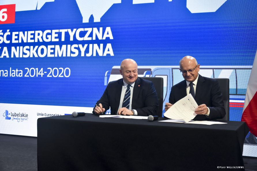 Przy stole umowy podpisują marszałek Jarosław Stawiarski i prezydent Krzysztof Żuk. W tle grafika działania 5.6 efektywność energetyczna i gospodarka niskoemisyjna.