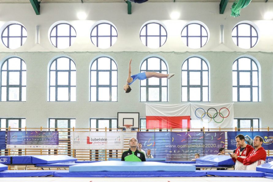 zawodnik podczas OOM w gimnastyce na trampolinie wykonujący ewolucje w powietrzu