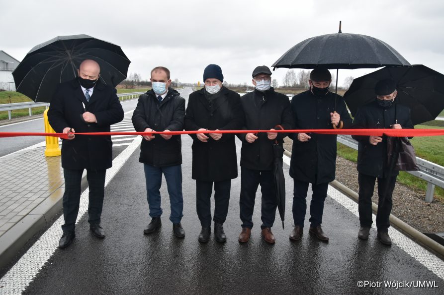 Od lewej Marszałek Jarosław Stawiarski, dyrektor zarządu dróg wojewódzkich Paweł Szumera oraz przedstawiciele samorządowców i wykonawców przecinają wstęgę.