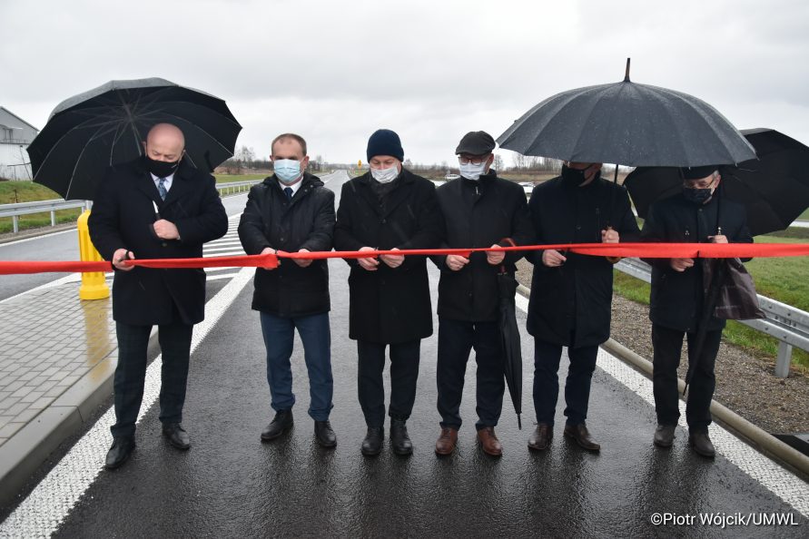 Od lewej Marszałek Jarosław Stawiarski, dyrektor zarządu dróg wojewódzkich Paweł Szumera oraz przedstawiciele samorządowców i wykonawców przecinają wstęgę.