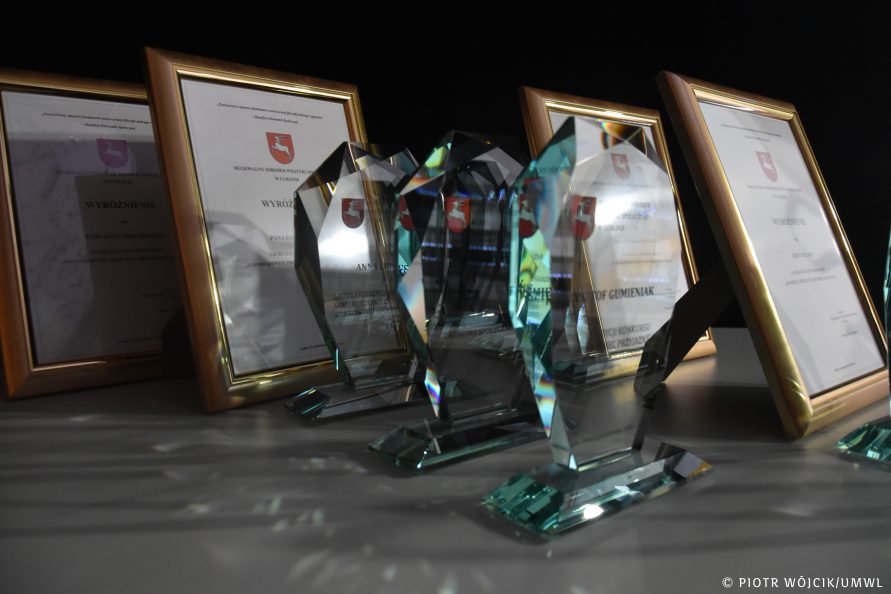 ramki z dyplomami i ozdobne szklane statuetki.