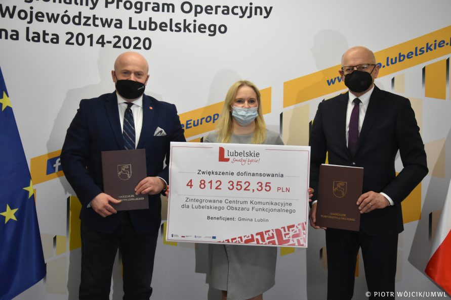 Od lewej stoją marszałek Jarosław Stawiarski, dyrektor departamentu Zarządzania Regionalnym Programem Operacyjnym Anna Brzyska (trzyma symboliczny czek z wypisaną kwotą dofinansowania - 4 812 352,35 zł) prezydent Krzysztof Żuk. W tle ścianka Regionalnego Programu Operacyjnego Województwa Lubelskiego na lata 2014-2020 w kolorystyce biało-żółto-pomarańczowej. Po obydwu bokach ścianki flagi Polski i Unii Europejskiej