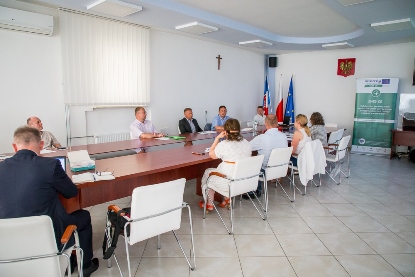 uczestnicy warsztatu przy stole obok roll-up projektu