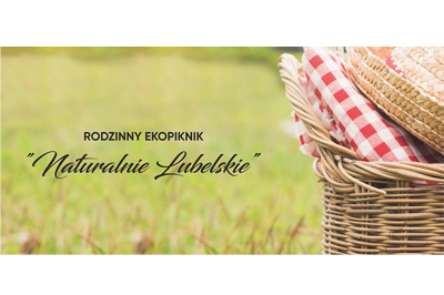 Zdjęcie pokazuje zieloną łąkę (rozmytą), z prawej w polu ostrości kosz piknikowy z wilkiny z serwetą w biało-czerwoną kratę. Po środku czarny napis w dwóch wersach "Rodzinny ekopiknik Naturalnie Lubelskie"