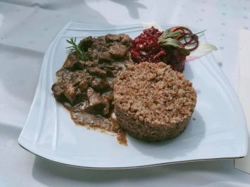 Danie z dziczyzny zaprezentowane na białym talerzu z dodatkiem kaszy gryczanej oraz buraczków