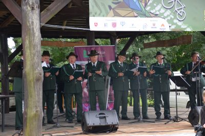Męski chór ubrany w galowe mundury myśliwych i kapelusze na głowie