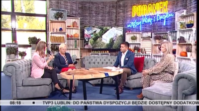 Zdjęcie przedstawiające 4 siedzące osoby na kanapie w kolorze szarym w tym jedną osobę Doradcę Energetycznego siedzącą po lewej stronie z mikrofonem, który przedstawia założenia programu Czyste Powietrze. W tle na ścianie napis PORANEK w kolorze żółtym, poniżej napis między Wisłą i Bugiem w kolorze niebieskim.