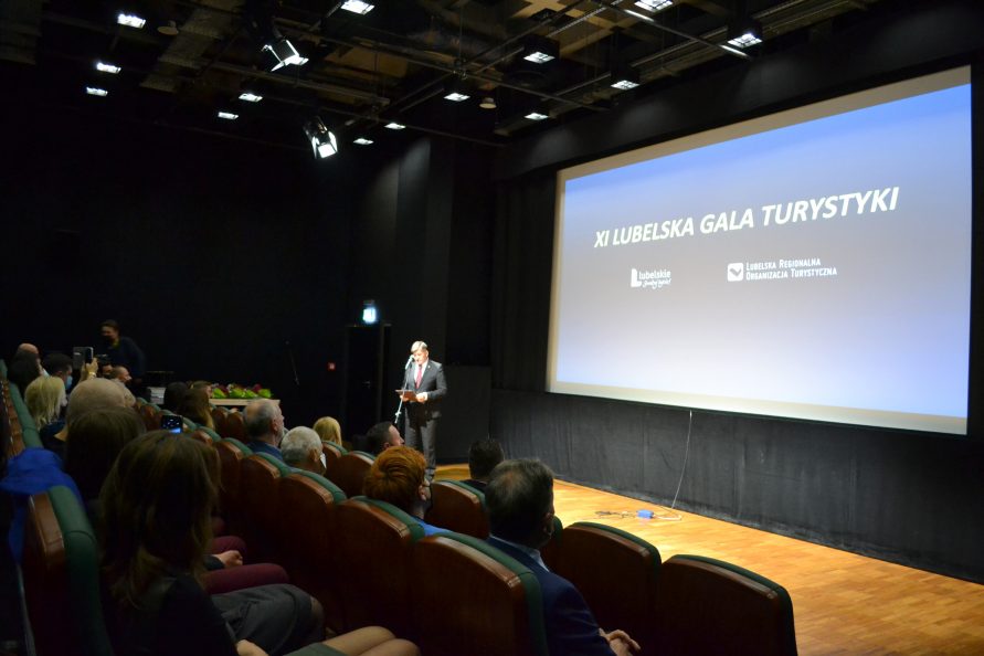Sala konferencyjna, na widowni słuchacze, na scenie Pan, w tle napis XI Lubelska Gala Turystyki