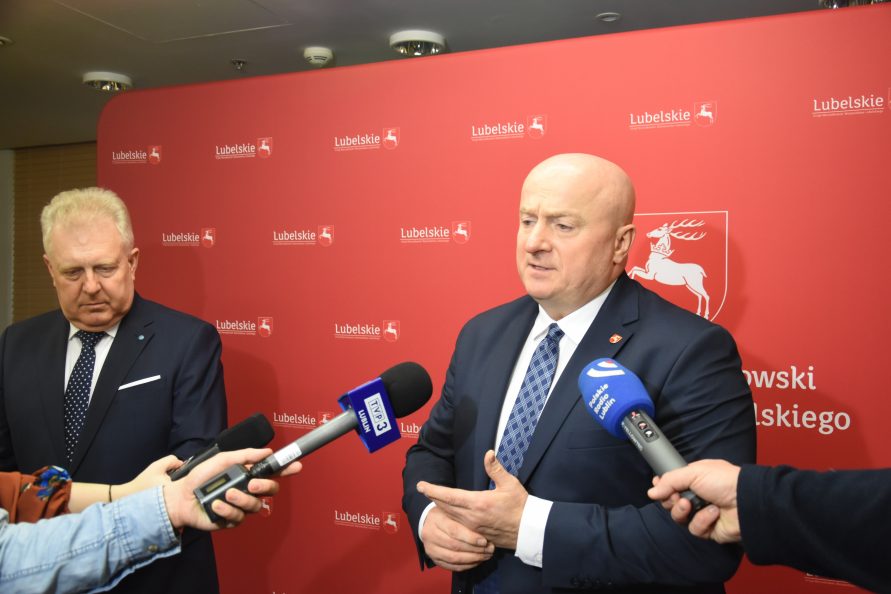 Zdjęcie przedstawia dwóch mężczyzn stojących na ściance promocyjnej Urzedu Marszałkowskiego. po lewej stronie stoi Dyrektor Wojewódzkiego Szpitala specjalistycznego w Lublinie Pan Piotr Matej a obok niego stoi Marszałek Województwa Lubelskiego Jarosław Stawiarski. Obaj Panowie udzielają wywiadu dziennikarzom.