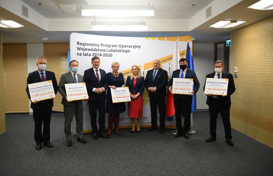 Zdjęcie przedstawia grupę ludzi, zarówno kobiet jak i mężczyzn stojących obok siebie