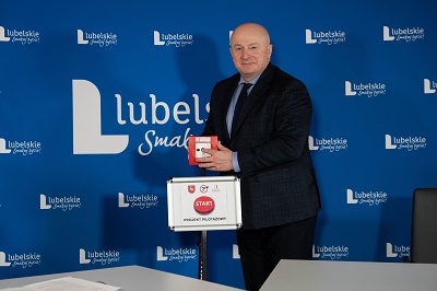 Zdjęcie przedstawia meżczyznę stojącego na tle ścianki z napisami Lubelskie