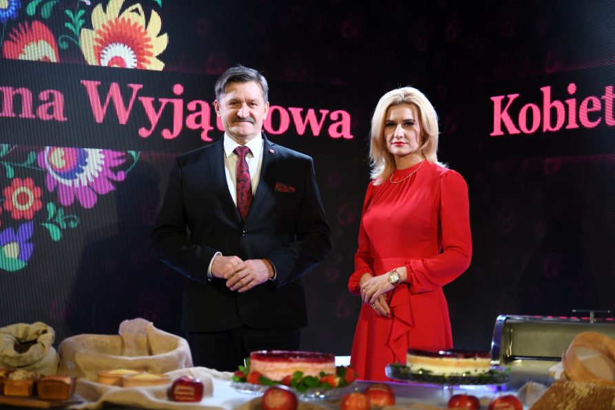 Zdjęcie przedstawia kobietę i mężczynę którzy stoją naprzeciwko stołu na którym są ustawione regionalne potrawy