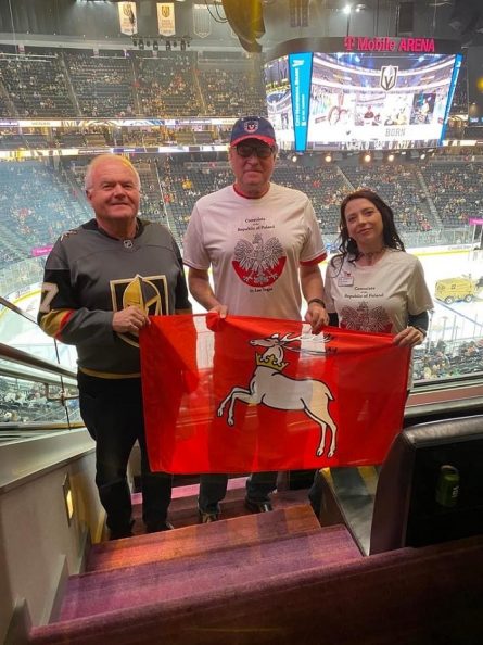 Zdjęcie przedstawia trzy osoby dwóch meżczyzn i kobietę którzy trzymają w rękach rozwinietą flagę województwa lubelskiego, w tle widać wnętrze stadionu sportowego