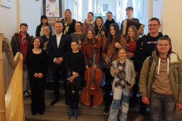 Grupa młodzieży stojąca do zdjęcia, niektórzy trzymają w rękach instrumenty muzyczne