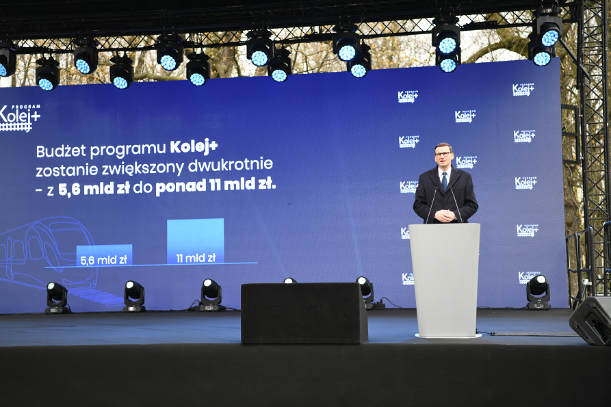 Scena z telebimem w tle oraz reflektorami umocowanymi na jej górze. Na scenie stoi mężczyzna i wygłasza przemówienie do mikrofonu.