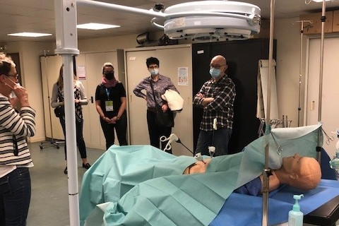 Kilka osób stoi w medycznej sali wykładowej i ogląda sprzet medyczny