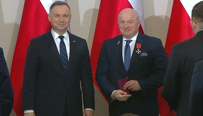 Dwóch mężczyzn stoi obok siebie, od lewej to Prezydent Polski Andrzej Duda a bok niego Jarosław Stawiarski Marszałek województwa Lubelskiego. Pan Marszałek trzyma w dłonich otrzymane odznaczenie, za nimi znajduja sie ustawione polskie flagi