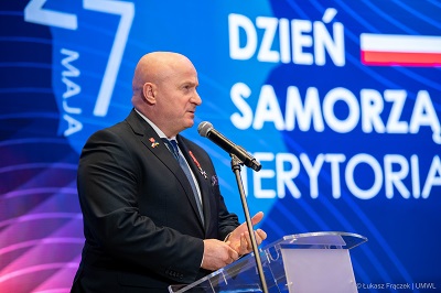 Marszałek Województwa Lubelskiego Jarosław Stawiarski stoi przy mikrofonie i udziela wypowiedzi, za nim na dużym ekranie wyświetla sie napis: Dzień Samorzadu Terytorialnego