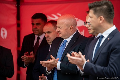 Pięciu mężczyzn stoi pod namiotem, patrzą w jednym kierunku ustawieni lewym profilem i klaszczą w dłonie