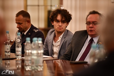 Widok na trzech mężczyzn siedzących przy stole przed nimi stoi butelkowana woda