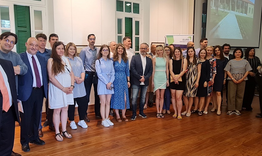 grupa ludzi stojąca na tle roll-upu projektu EURE