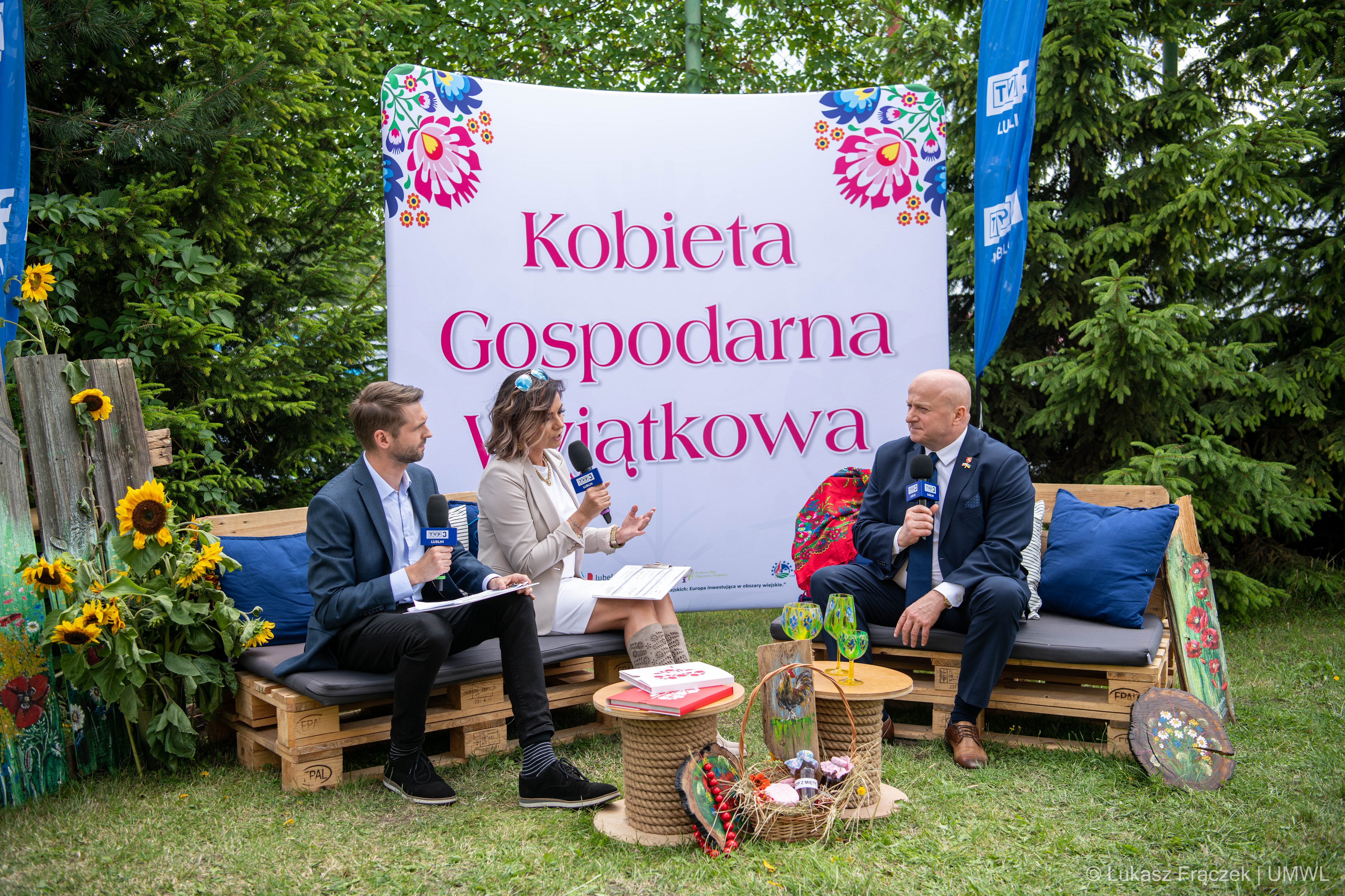 Na zewnątrz wśród drzew dwójka dziennikarzy przeprowadza wywiad z Marszałkiem Województwa Lubelskiego