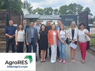 uczestnicy spotkania na tle budynków gospodarczych z panelami fotowoltaicznymi