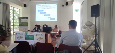 sala konferencyjna, widok na prelegenta mowiącego prezentację, roll-up z logo projektu z lewej