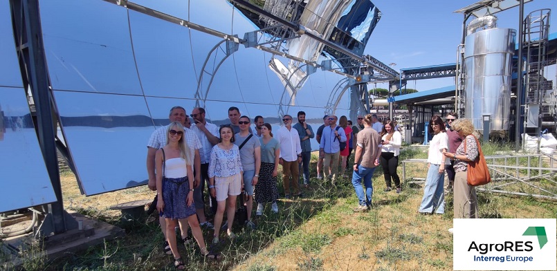 Uczestnicy spotkania na tle instalacji z luster skupiających promienia słońca