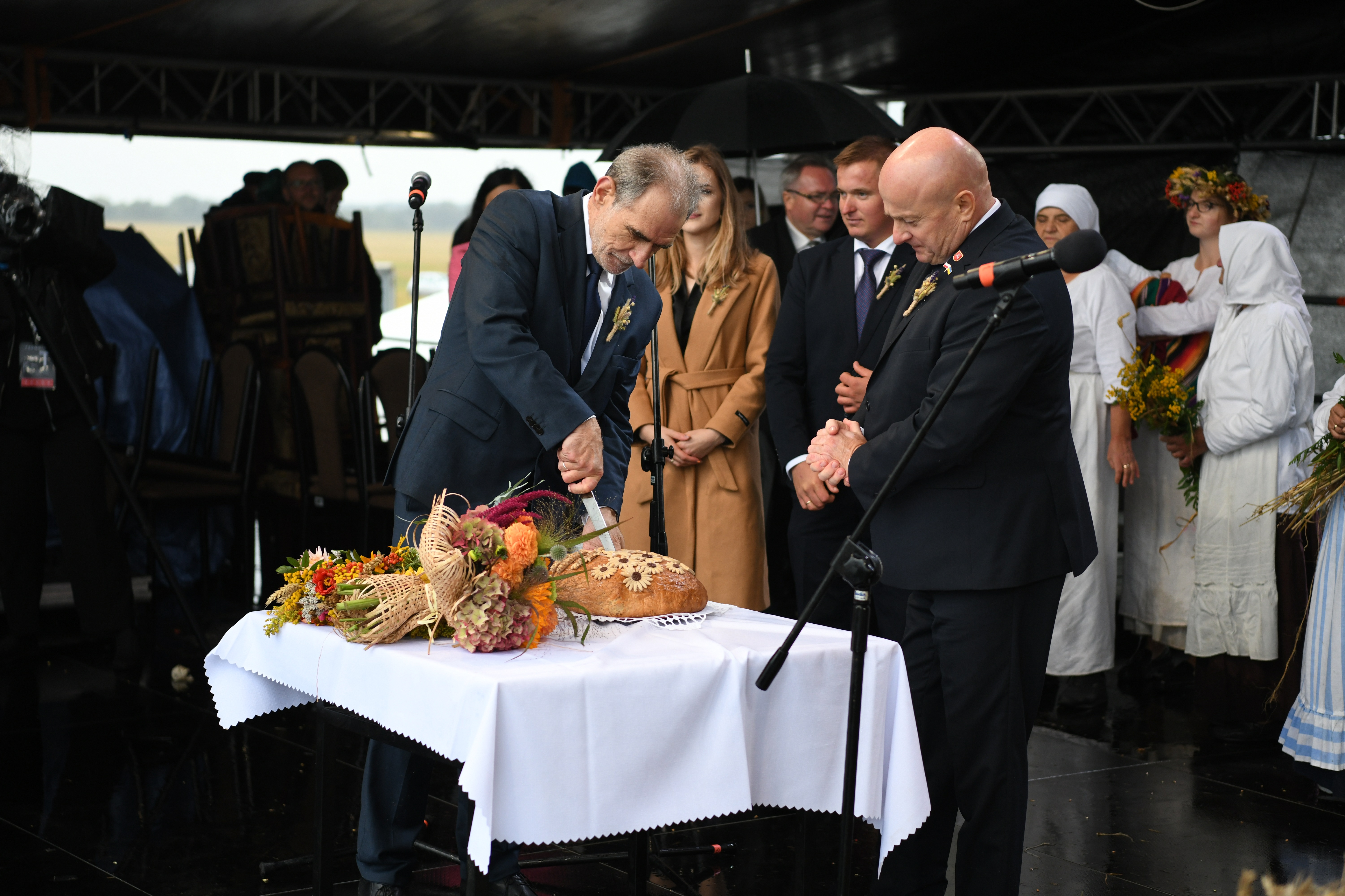 Marszałek WL i Starostwa Lubelski, w trakcie dożynek, stoją na scenie i kroją chleb