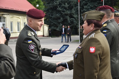 Plac wojskowy. Dowódca wręcza odznaczenie żołnierce