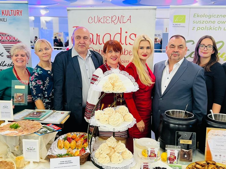 uczesnitcy targów kulinarnych na pierwszym planie stół z potrawami