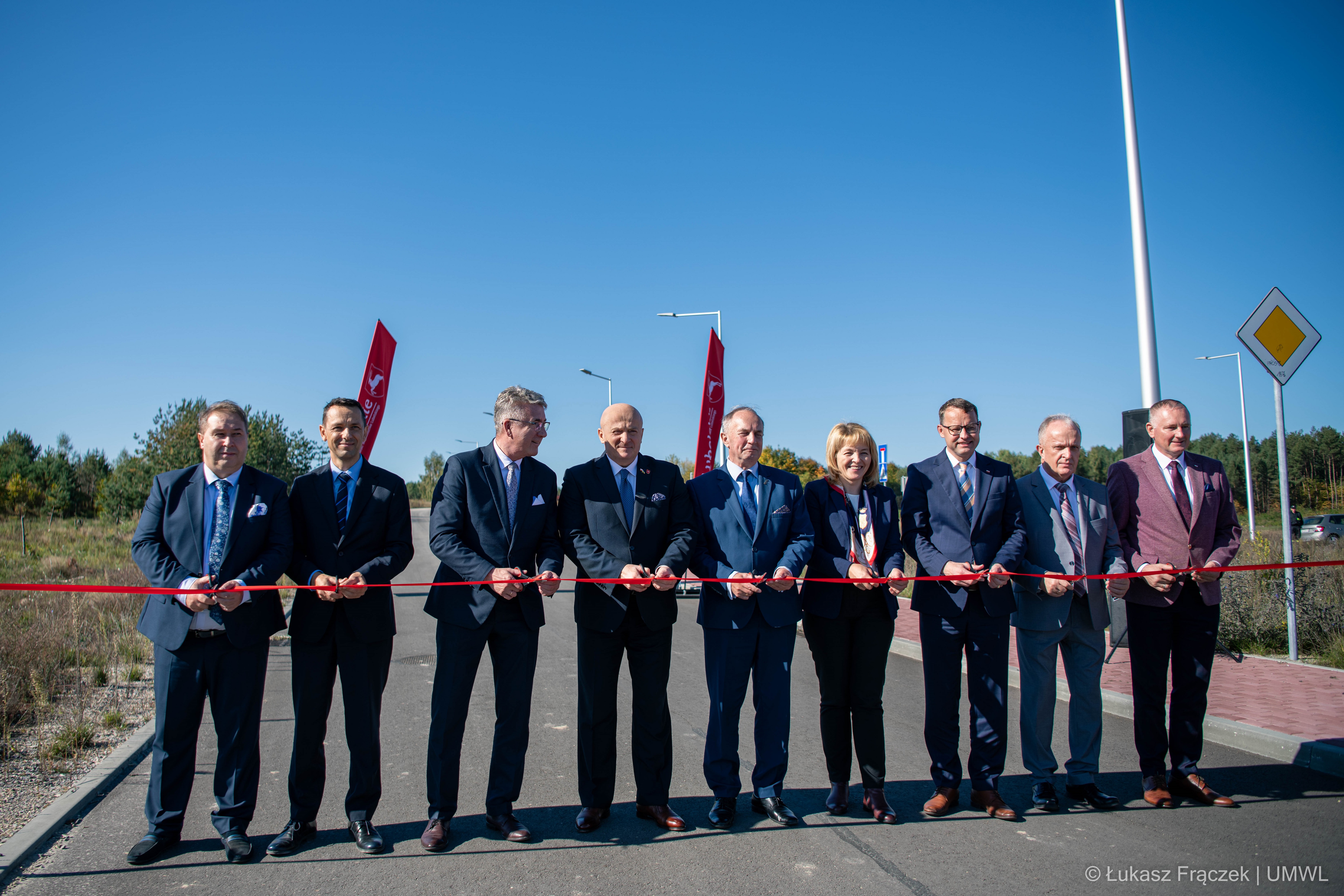 Grupa osób ustawiona do przecinania wstęgi