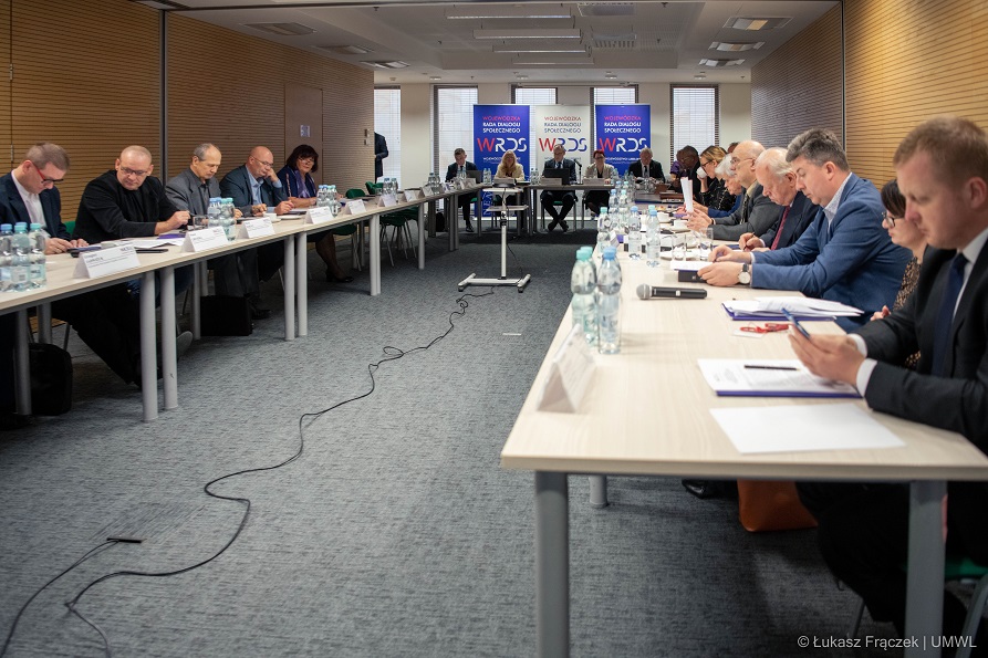 Członkowie rady siedzą przy stole ustawionym w podkowę