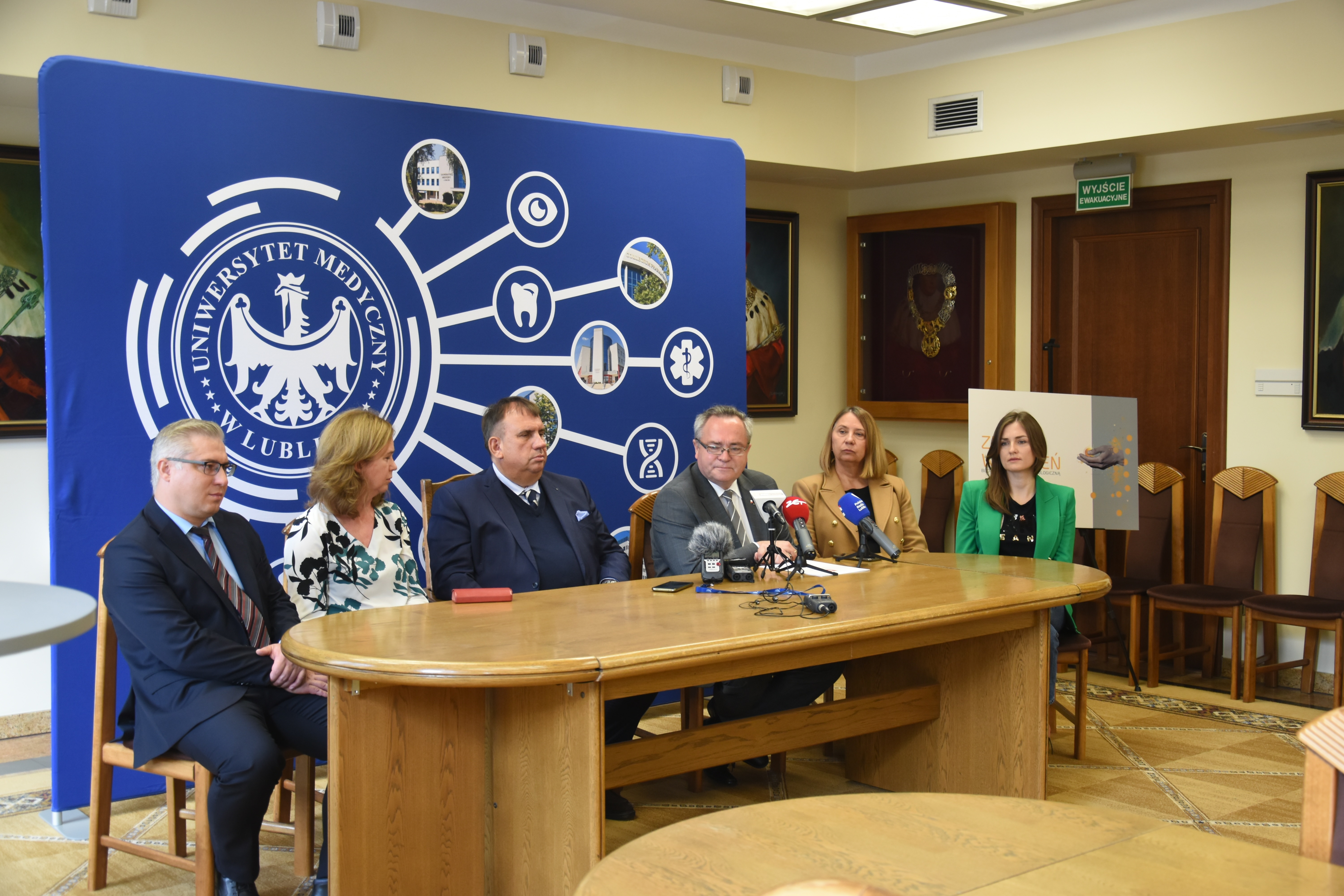 Marszałek WL stoi na dworze i udziela wypowiedzi do mikrofonu, na pierwszym planie operator z kamerą