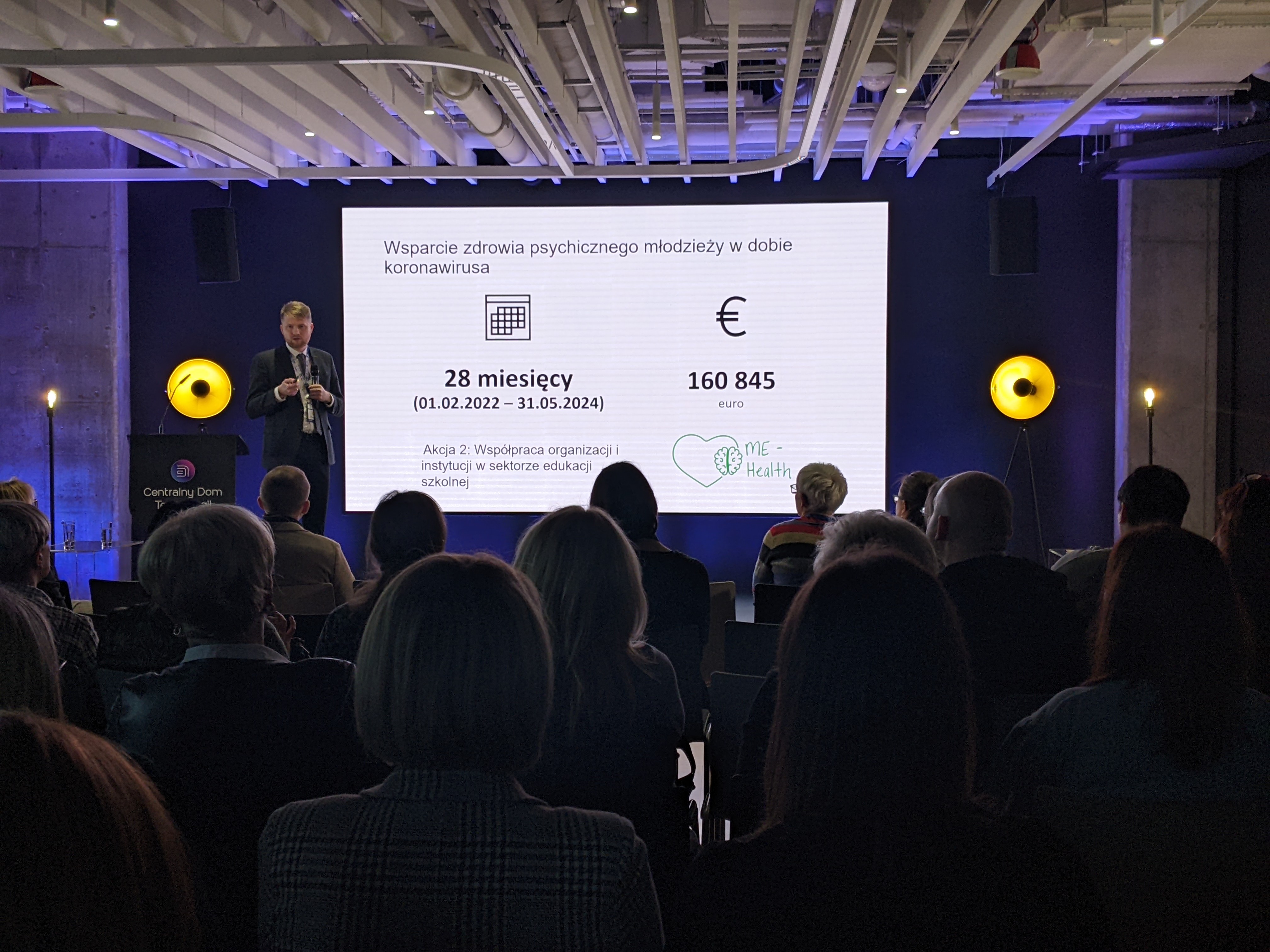 Widok na ekran z prezentacją i salę pełną uczestników wykładu