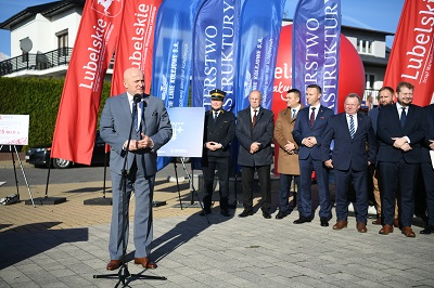 Marszałek WL stoi na zewnątrz przy mikrofonie i przemawia za nim zgromadzeni w trakcie spotkania