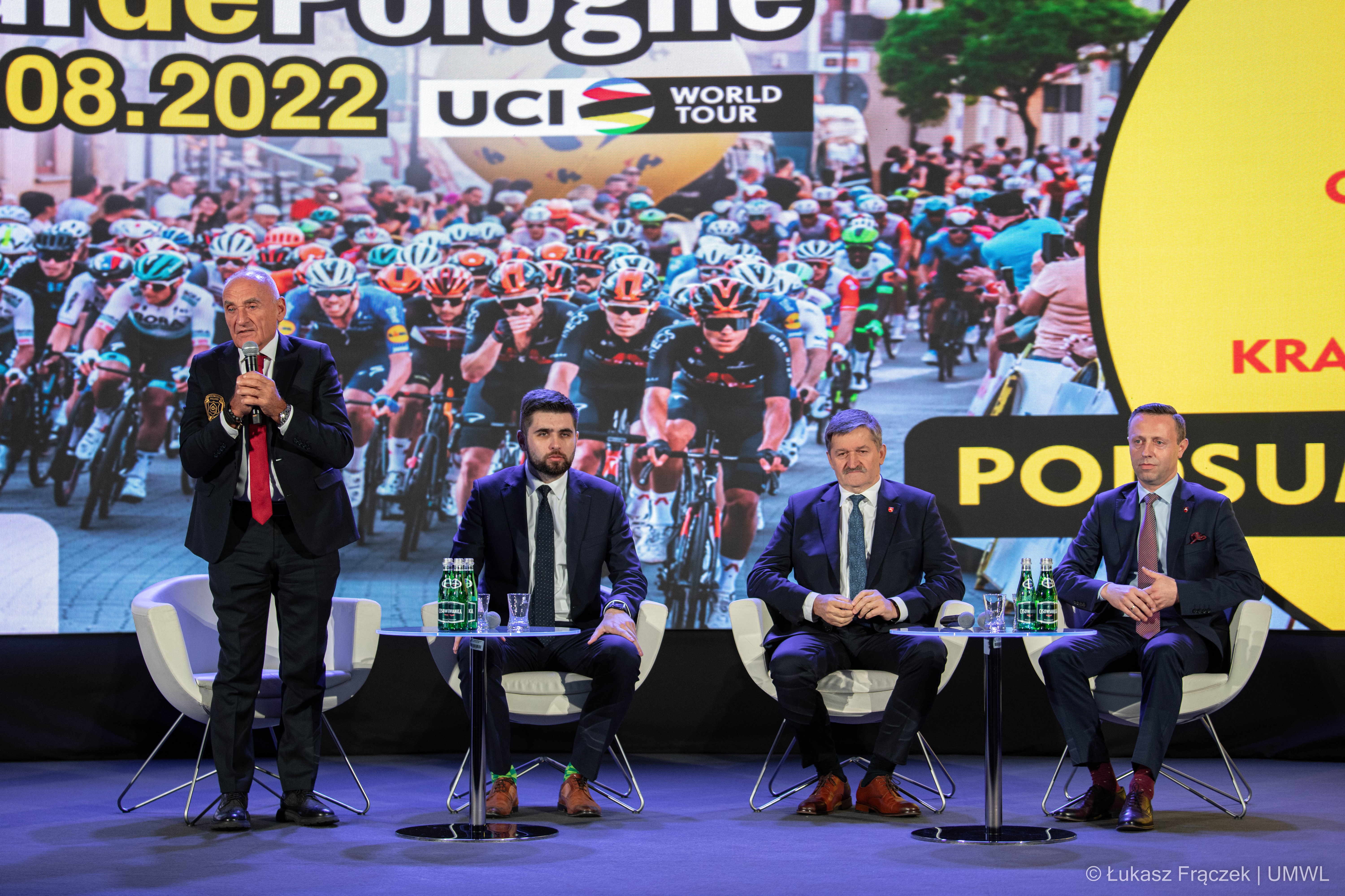 czesław lang wraz z przedstawicielami wUMWL w trakcie konferencji, w tle ekran wyświetlający kolarzy w trakcie wyścigu