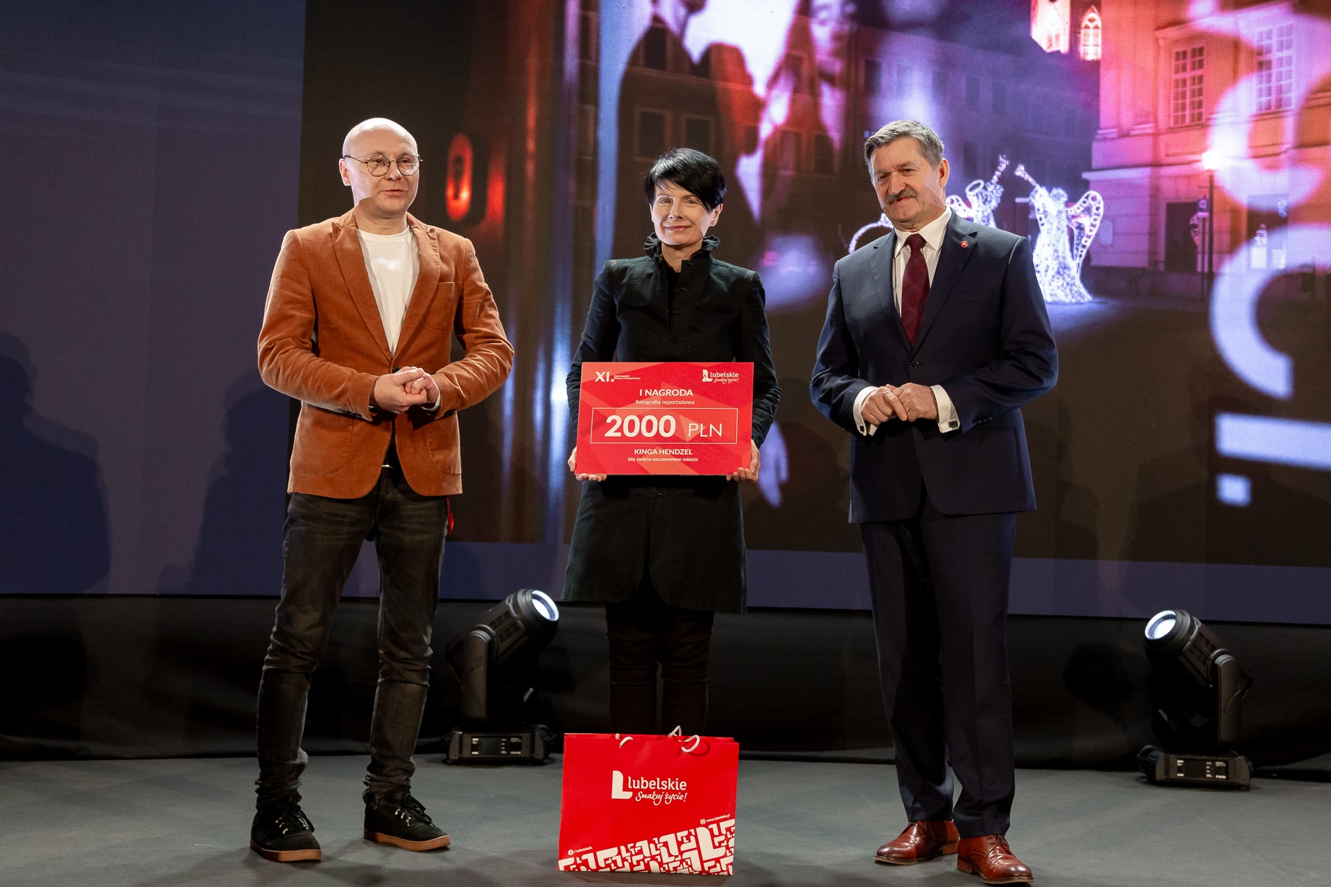 Laureatka konkursu fotograficznego na scenie odbiera nagrodę od członka zarządu Zdzisława Szweda