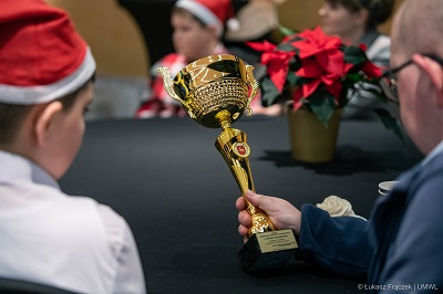 Mężczyzna trzymający w ręce puchar, obok siedzi chłopiec