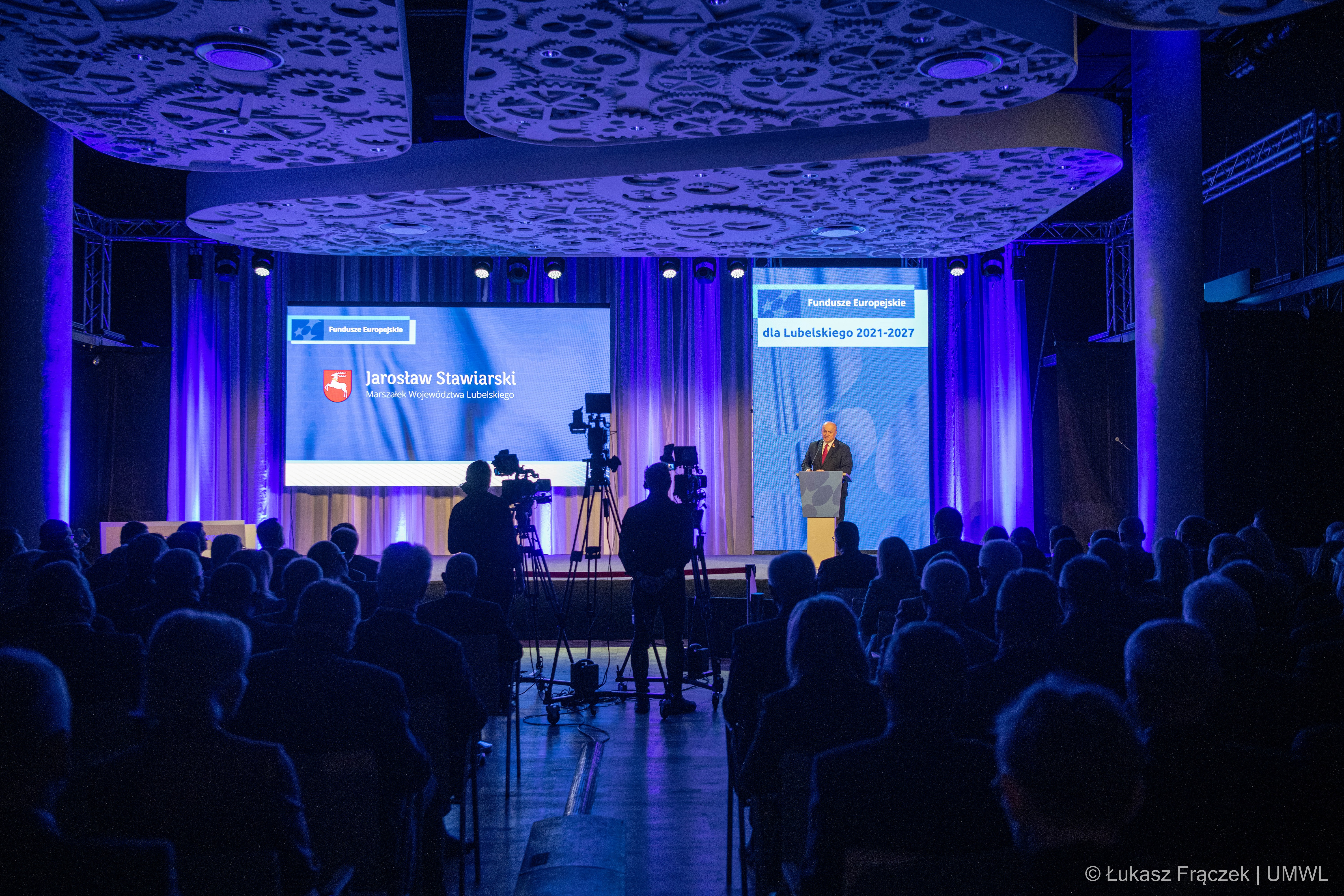 Widok na salę konferencyjną wypełnioną gośćmi. Na scenie stoi marszałek WL , który otwiera konferencję