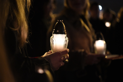Widok na zapalony znicz trzymany w rękach przez młodą kobietę