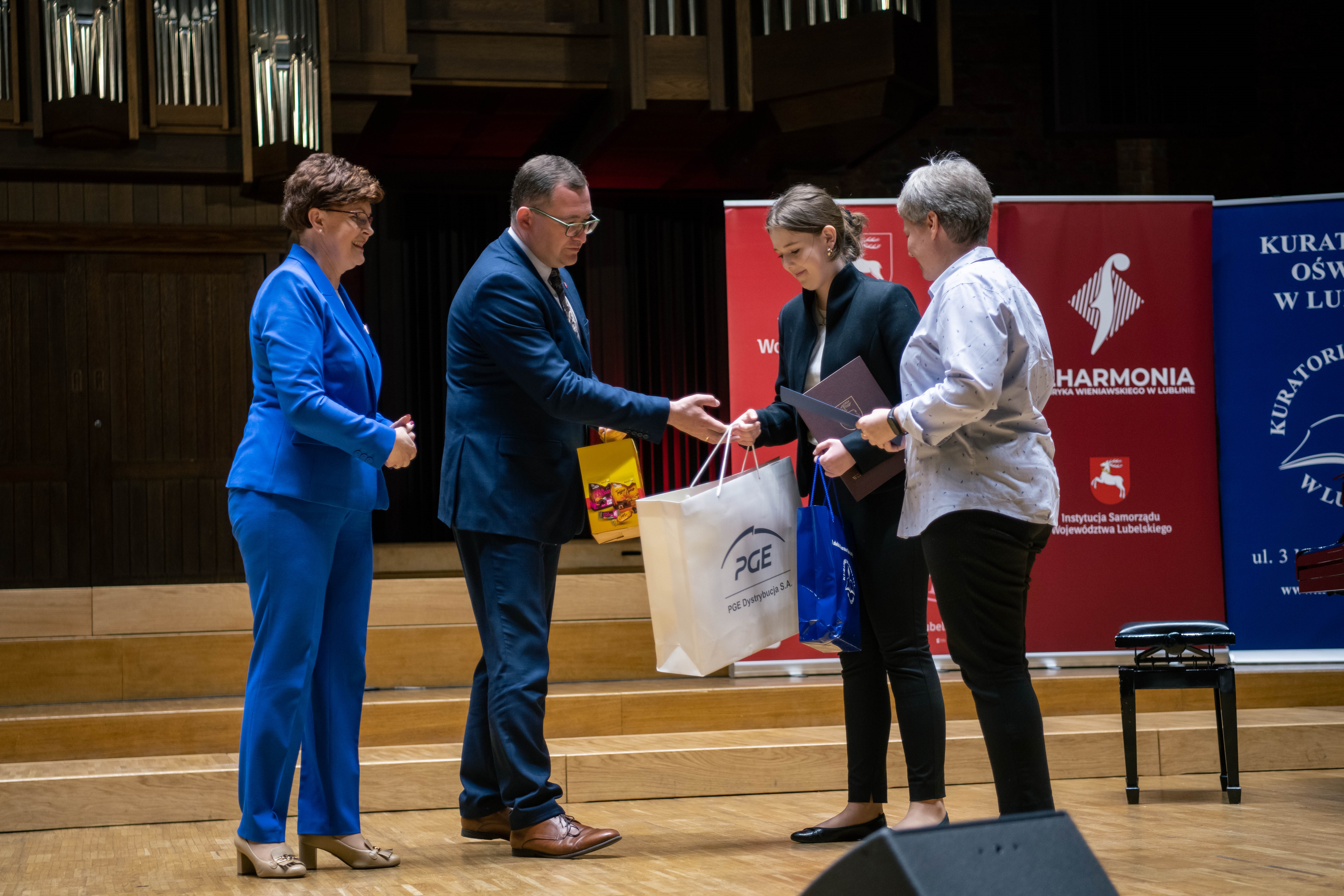 Członek Zarządu WL i Kurator Oświaty wręczają nagrody laureatom